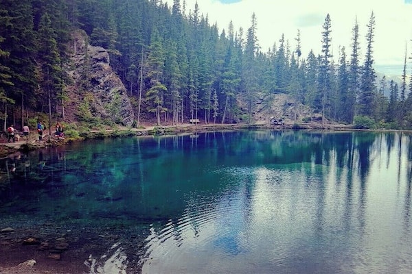 Ein klarer See, umgeben von dichtem Wald und felsigem Gelände.