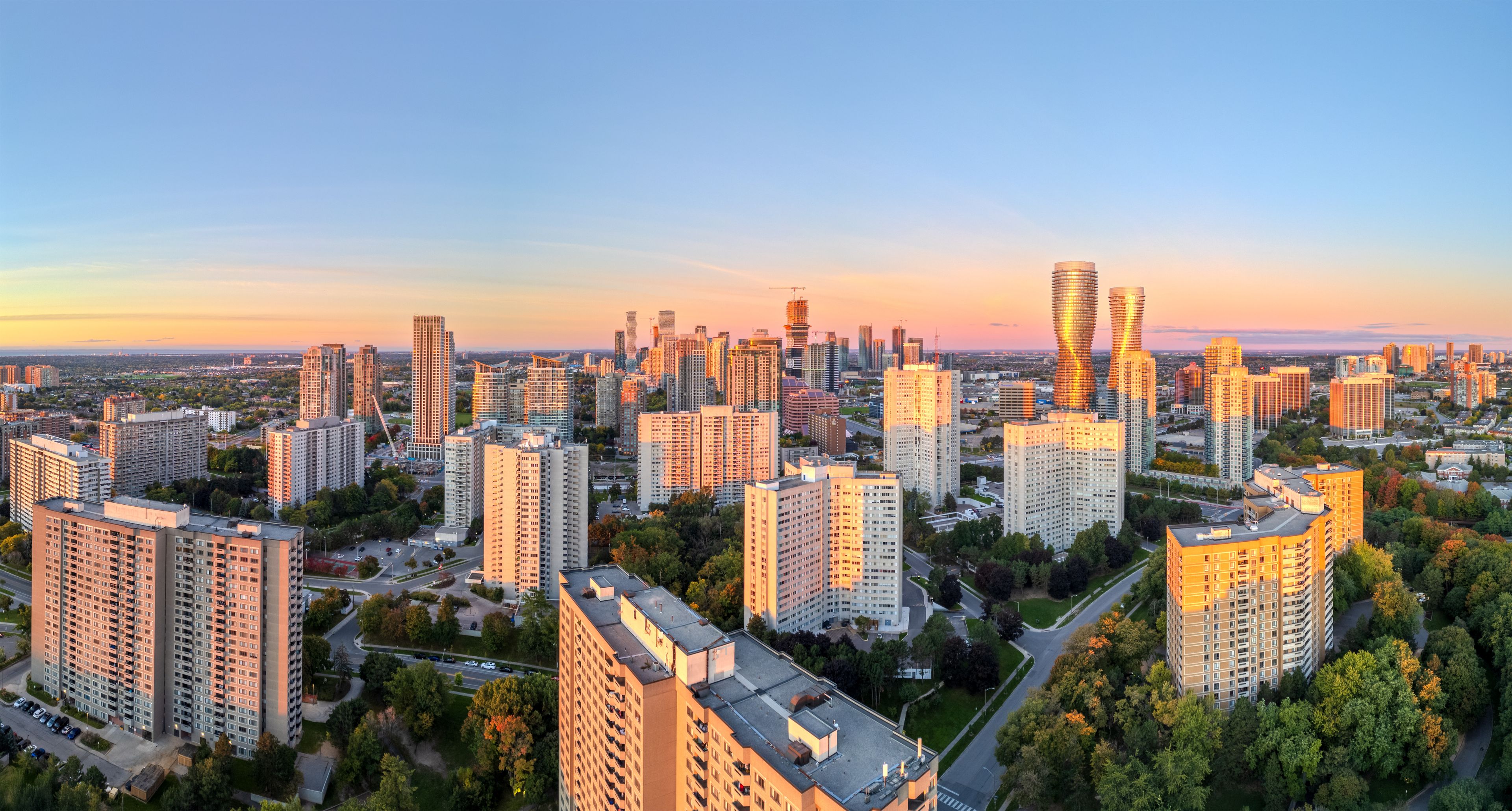 Stadtbild mit Wolkenkratzern und einem Sonnenuntergangshimmel.