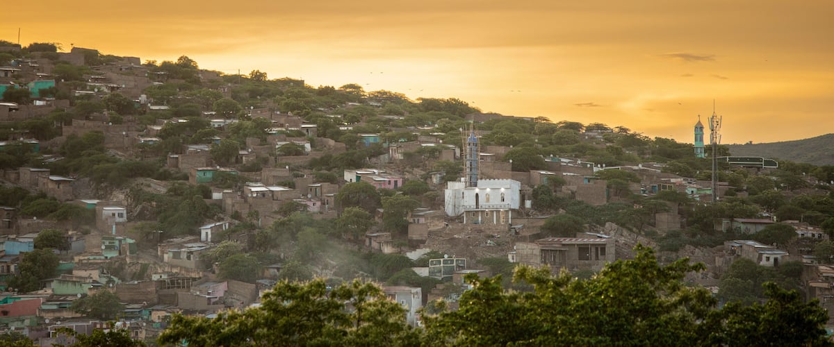 A hillside settlement with scattered buildings and a prominent white tower.