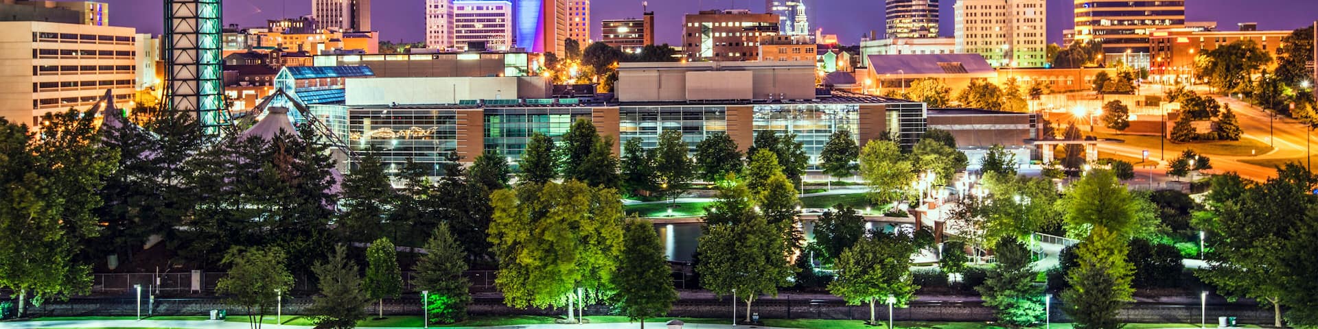 A city skyline at night with illuminated buildings and a prominent tower.
