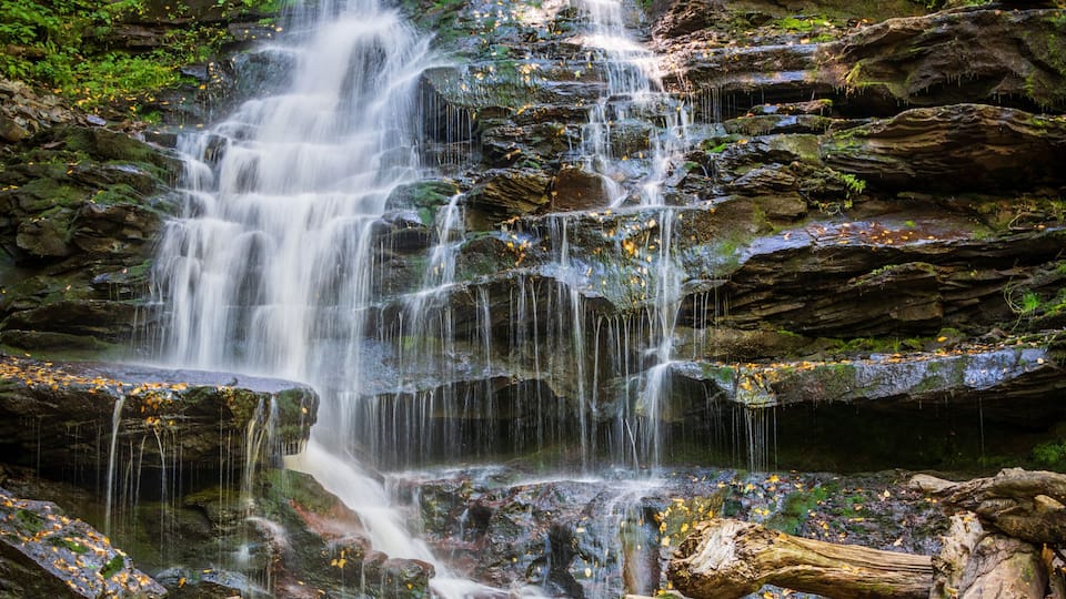 A multi-tiered waterfall surrounded by rocks and foliage.