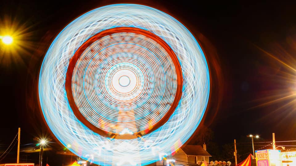 A large Ferris wheel with light trails at night.