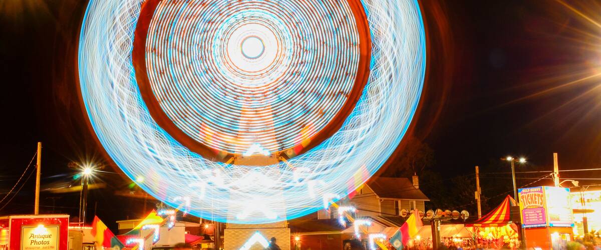 A large Ferris wheel with light trails at night.