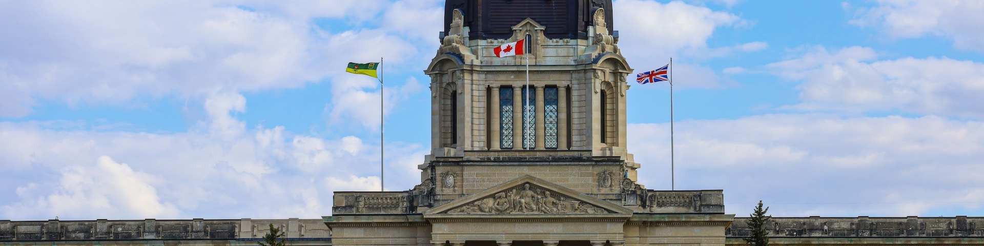 Un grand bâtiment gouvernemental, doté d’un dôme imposant et arborant plusieurs drapeaux.