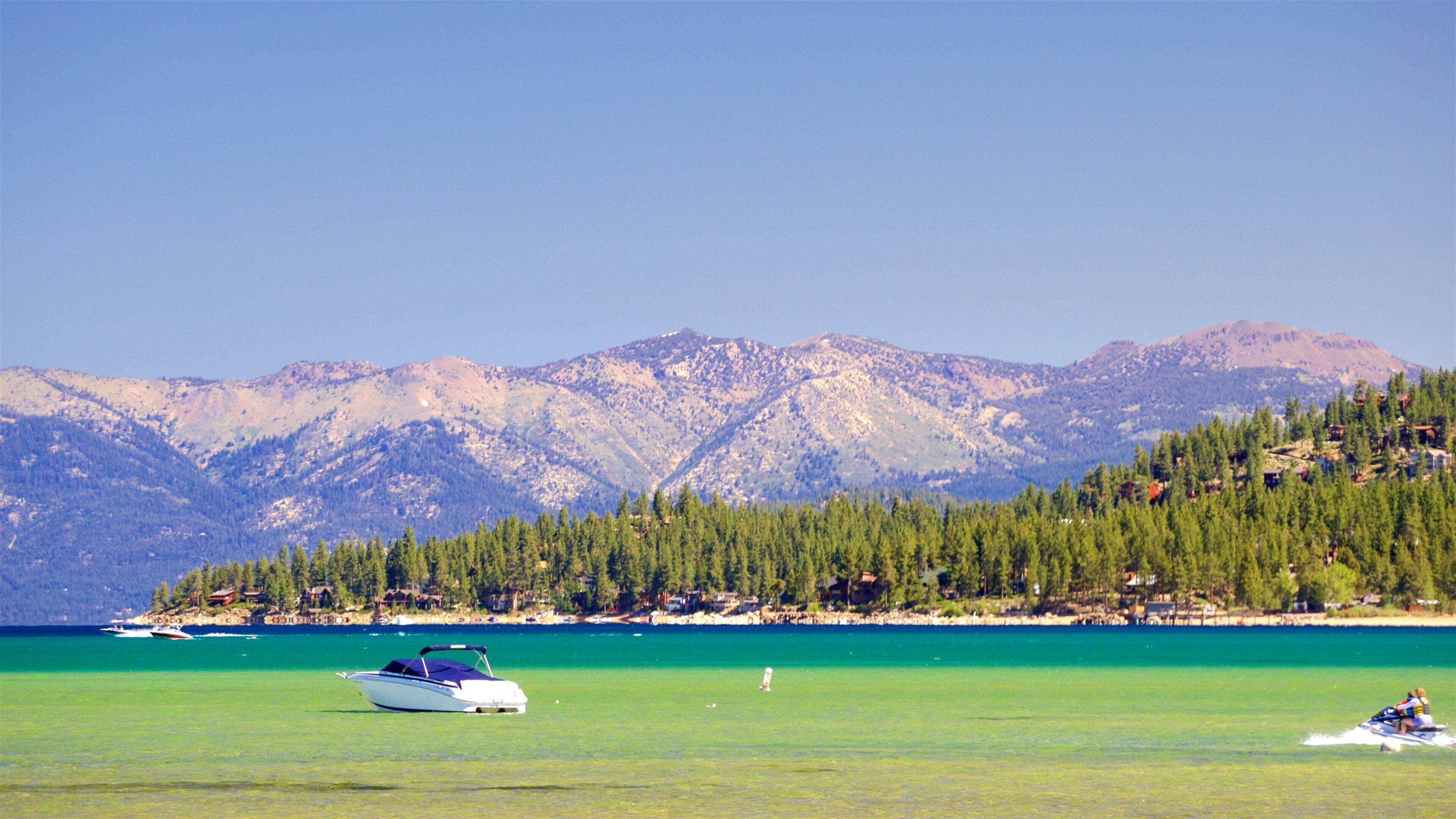 A boat on a turquoise lake with mountains in the background.