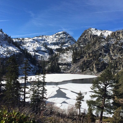 Paisagem montanhosa coberta de neve, com geleira e árvores.