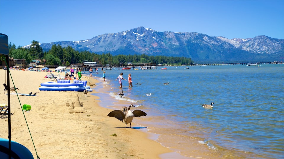 A beach with inflatable structures, people, and a mountain in the background.