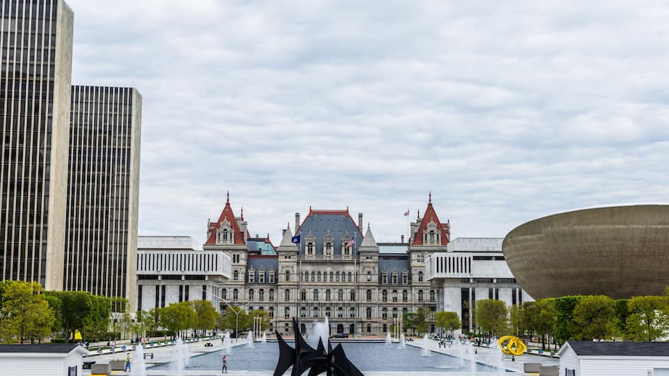A historic building with a fountain and a modern sculpture in front.