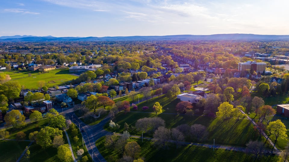 An aerial view of a suburban area with houses, roads, and green spaces.