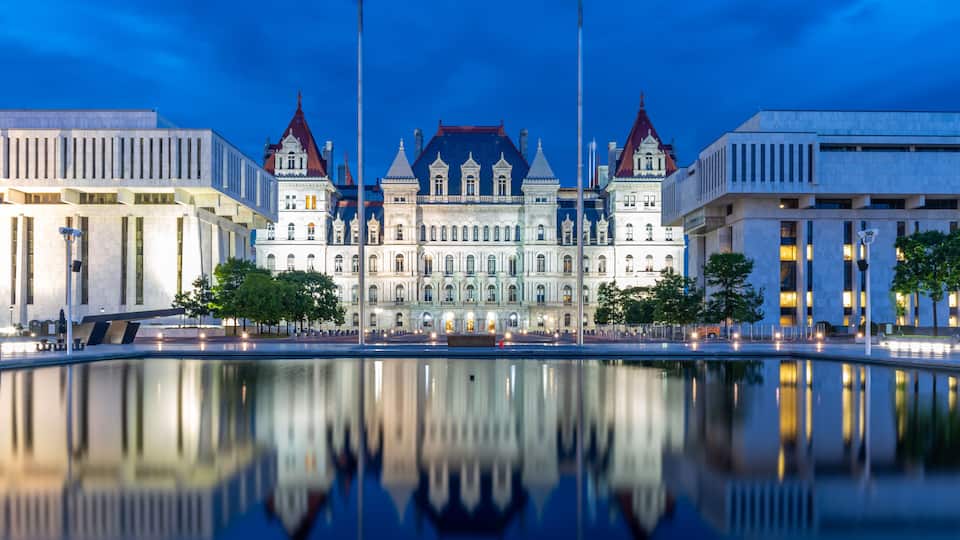 A historic building with ornate architecture and a reflective water body in front.