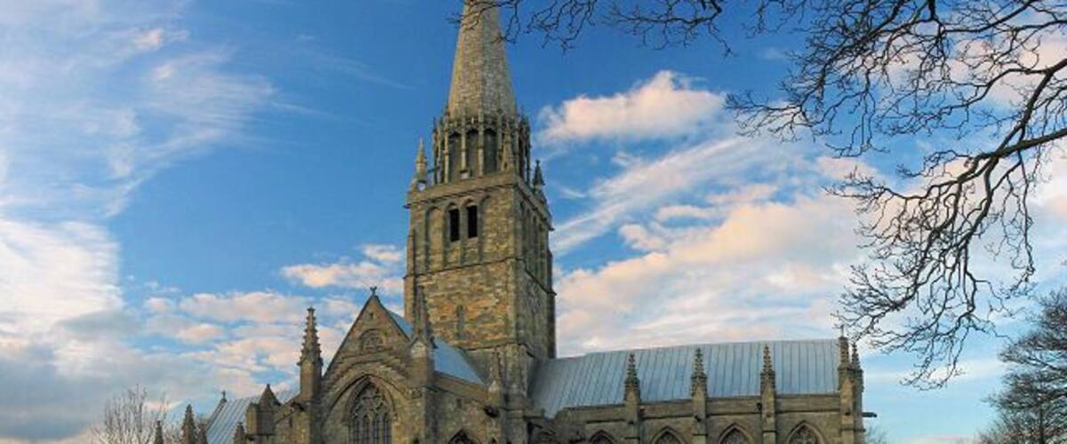 A historic church with a tall spire and a cemetery in front.