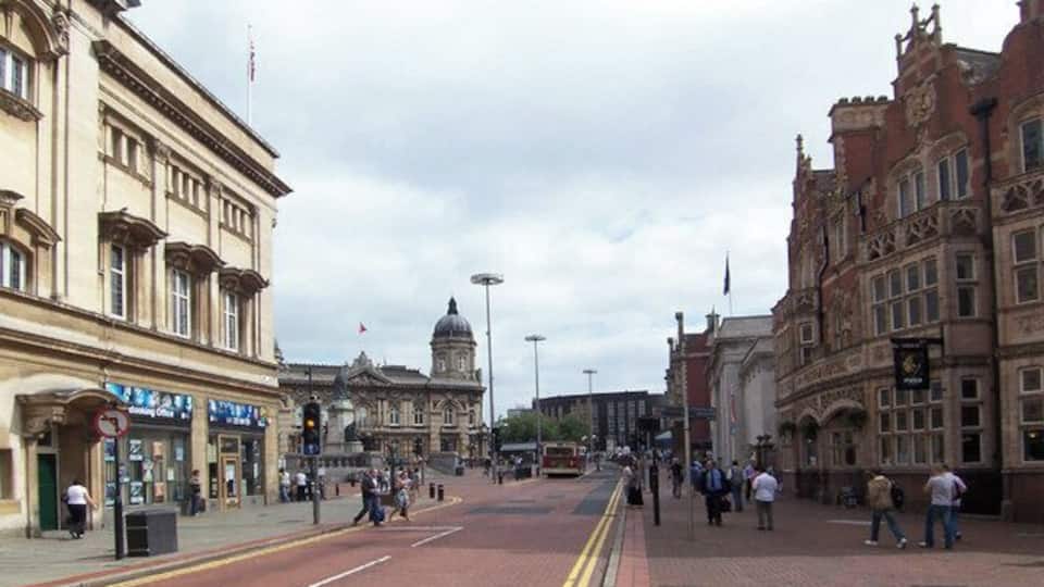 A wide street with historic buildings, a prominent dome, and a red brick pavement.