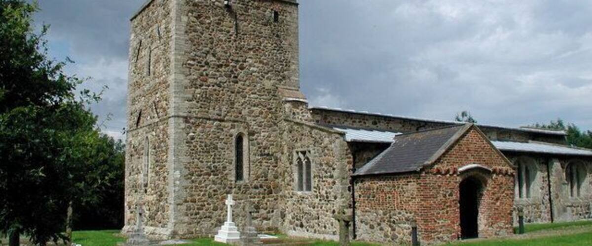 A stone church with a bell tower and a small adjacent building.