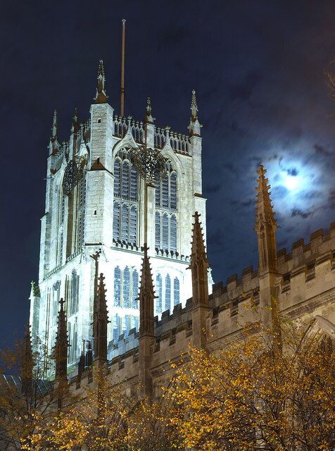 Een gotische kathedraal bij nacht, met een volle maan op de achtergrond.