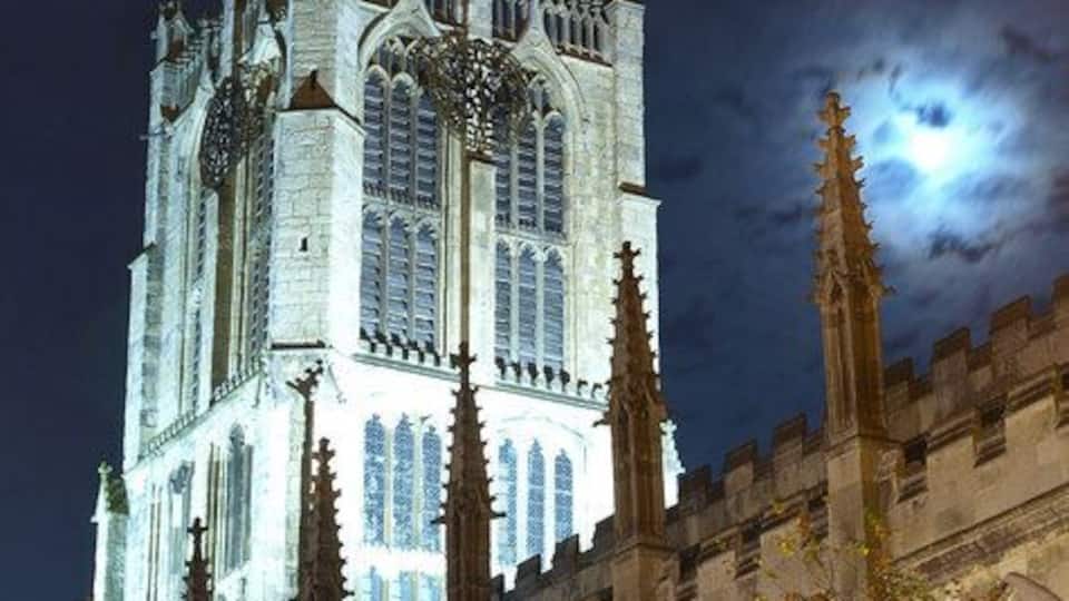 A Gothic-style cathedral at night with a full moon in the background.