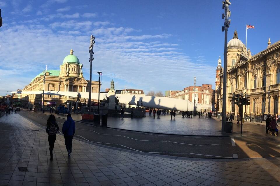 A wide, open square with historic buildings, including a prominent dome and clock tower.