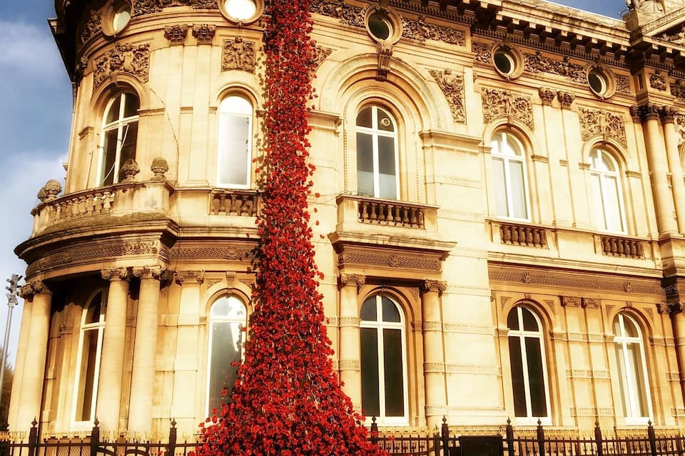 A historic building with ornate architecture and a large red flower-covered column.