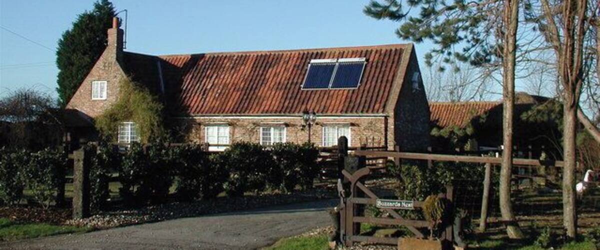 A rustic stone house with a sloped roof and a solar panel.