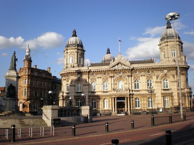 A historic building with two domes and statues in front.