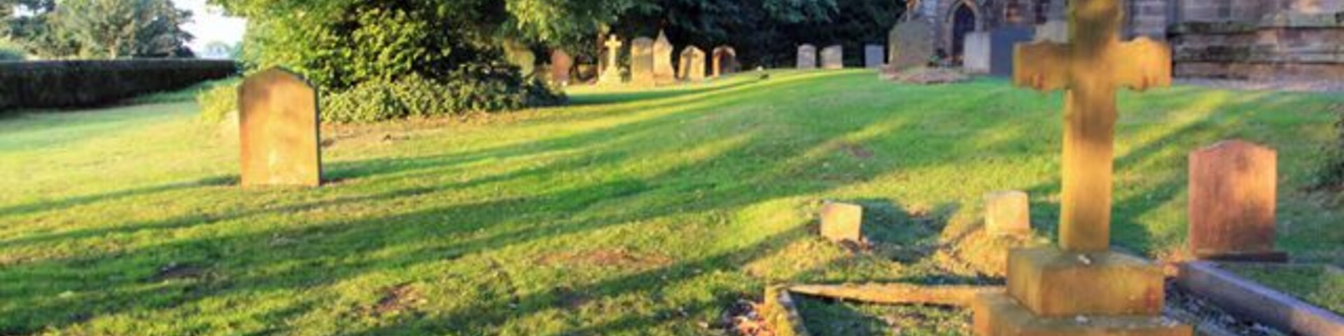 All Saints Churchyard, Rise, East Riding of Yorkshire, England. The area is bathed in warm evening light.