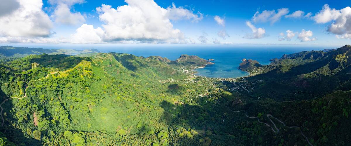 A lush green valley with a coastal town and a clear blue sky.