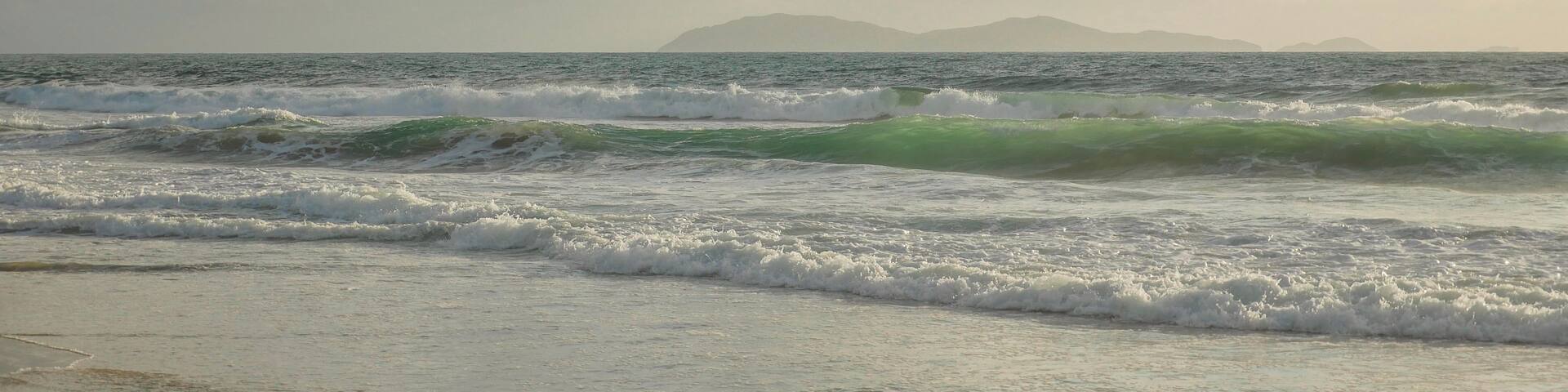 A beach with waves and a cloudy sky.