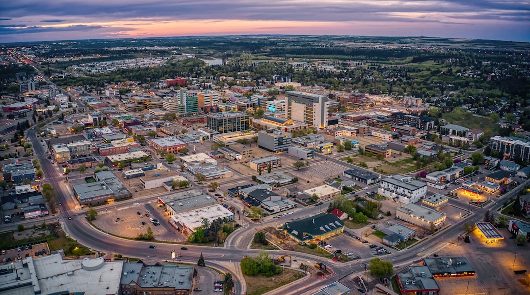 An aerial view of a city with a mix of commercial and residential buildings, a prominent shopping center, and a river in the background.