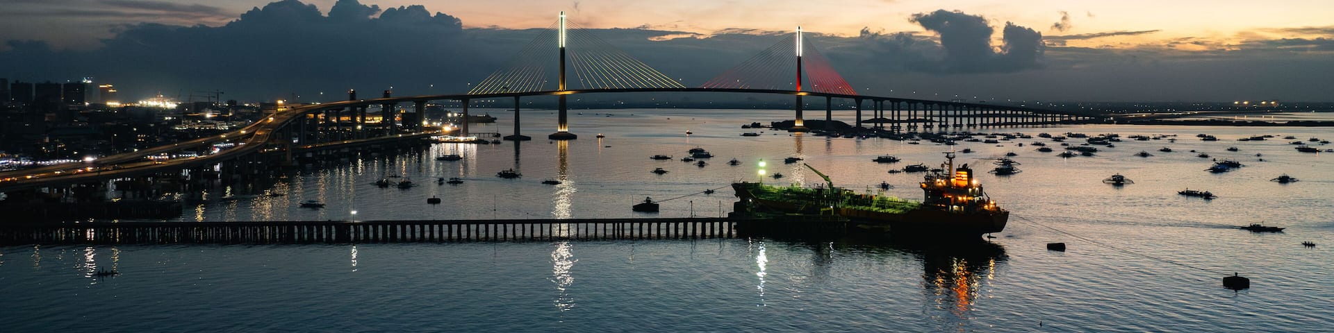 Aerial view of the iconic Marcelo Fernan Bridge stretches across the Mactan Channel as the sun sets, casting a golden glow on the water, Cebu City, Central Visayas, Philippines.