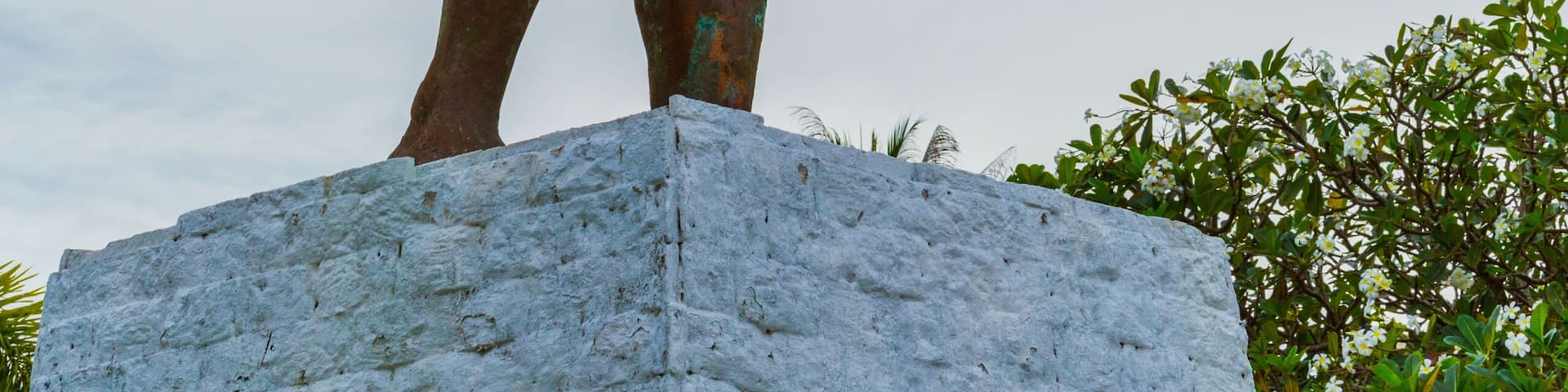 A bronze statue of a warrior holding a sword and shield, standing on a white pedestal.