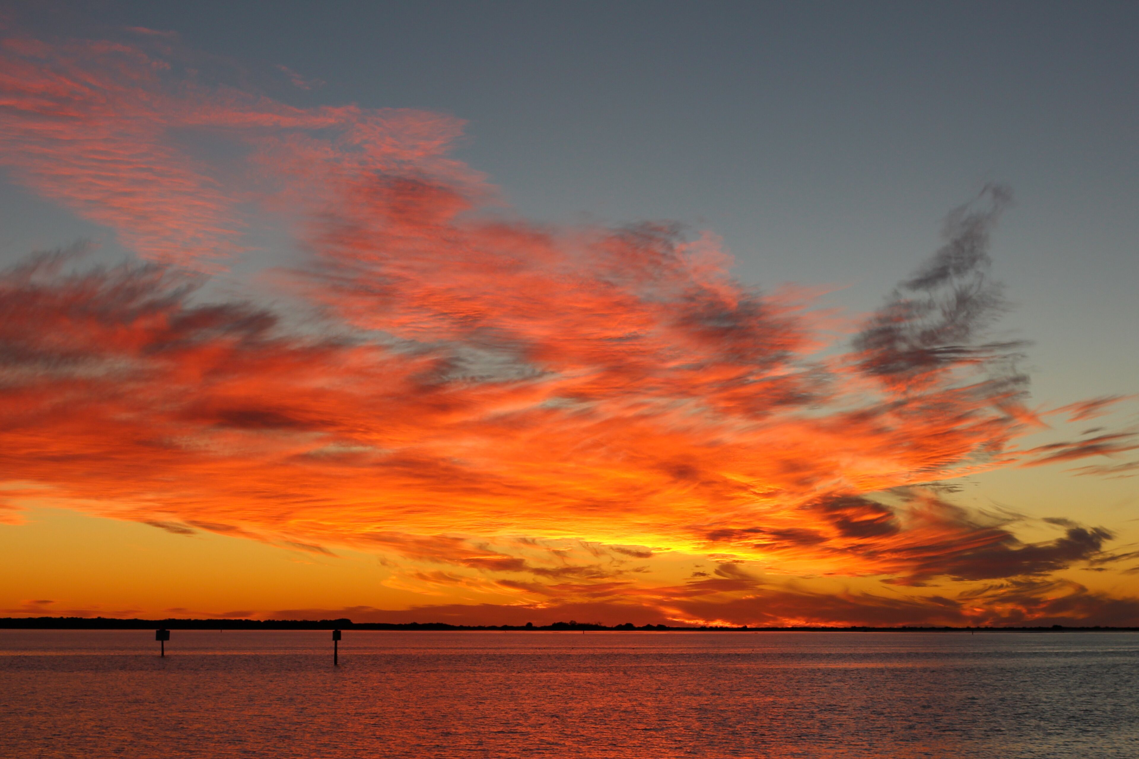 A sunset over a calm body of water with vibrant orange and red clouds.