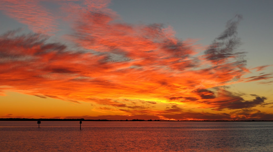 A sunset over a calm body of water with vibrant orange and red clouds.