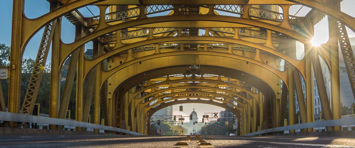 Eine gelbe Stahlbrücke mit einer Straße darunter.