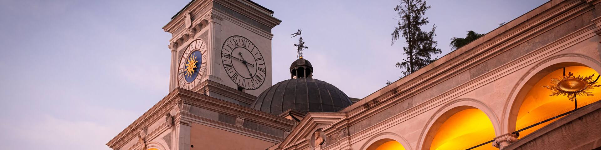 Beautiful classic Italian architecture at sunset. Magnificent clock tower, loggia, arches and colonnade in Udine city, Friuli Venezia Giulia region, Italy.