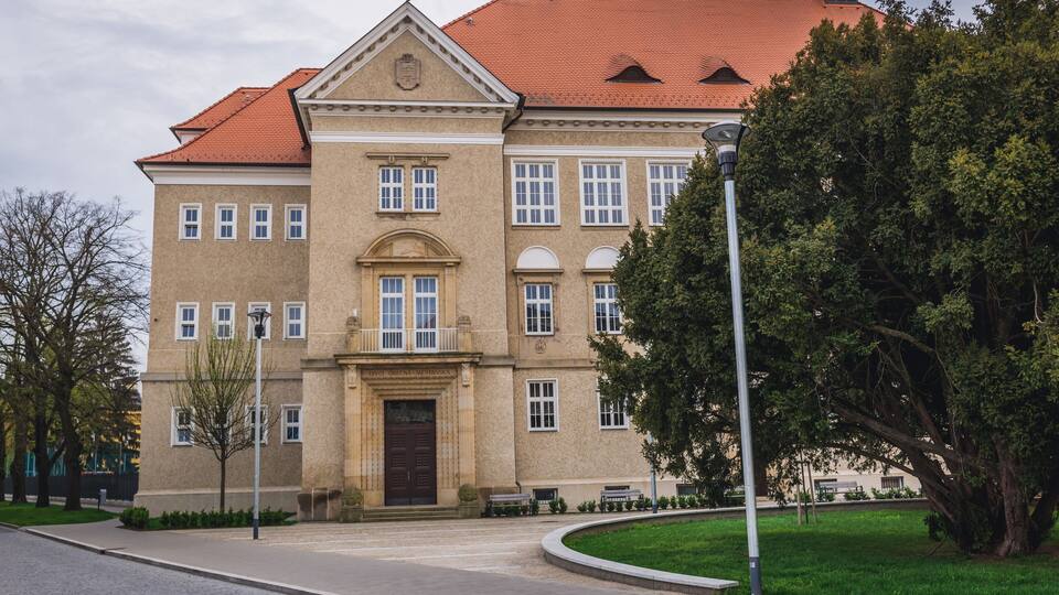 A large, historic building with a red-tiled roof and a symmetrical facade.