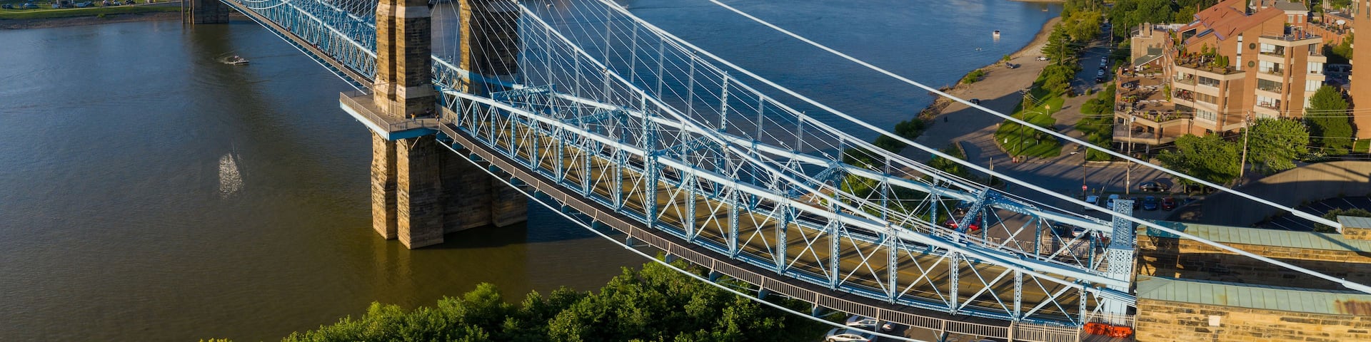 A suspension bridge over a river with a city skyline in the background.