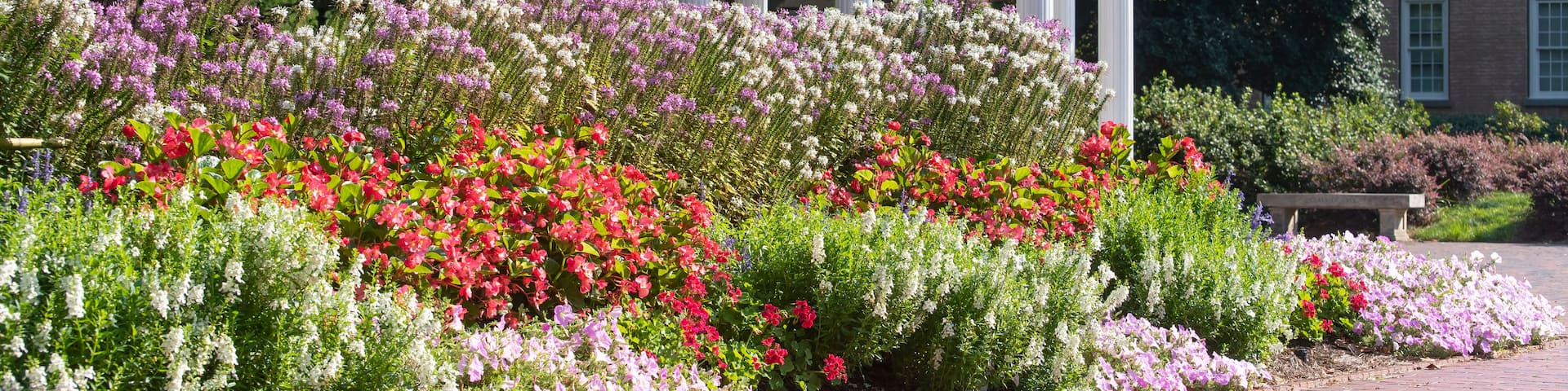 A garden with a white gazebo, colorful flowers, and a brick pathway.
