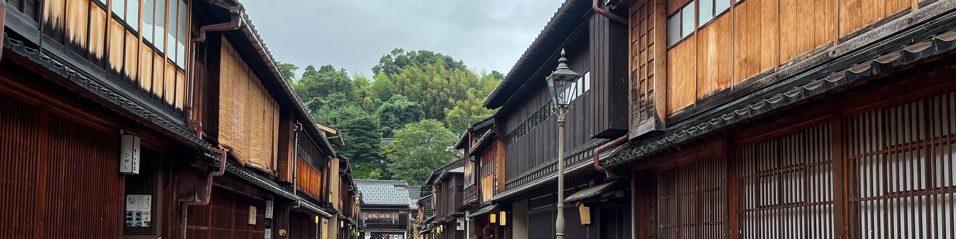 A traditional wooden street with tiled pavement, flanked by buildings with wooden facades and large windows.