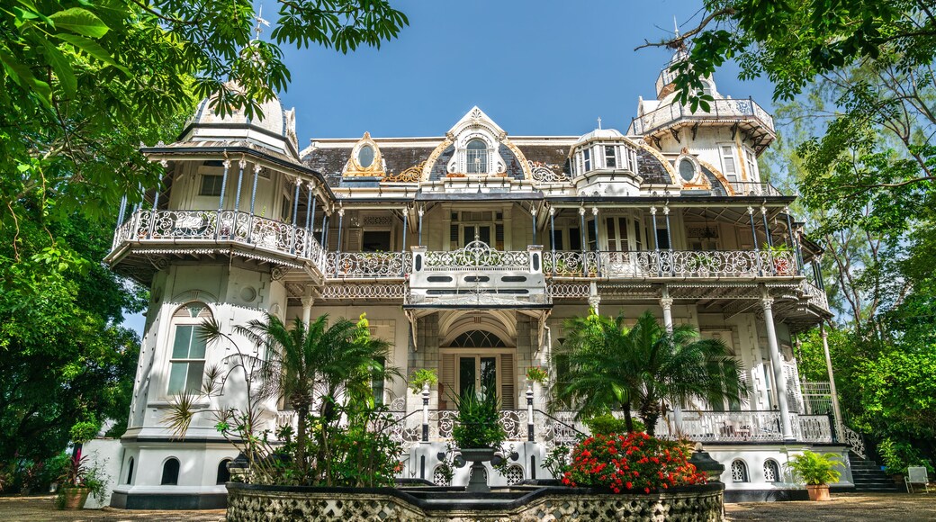 Un grand bâtiment imposant, richement décoré et doté de détails architecturaux complexes, entouré d’une végétation luxuriante.