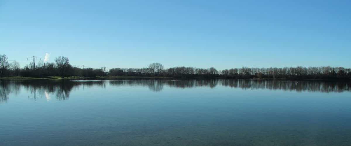 A calm lake with a clear reflection of the sky and trees.