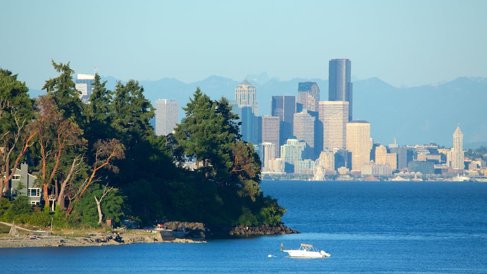 A coastal cityscape with a prominent skyline, including tall buildings and a Ferris wheel, surrounded by dense forests and a calm sea.