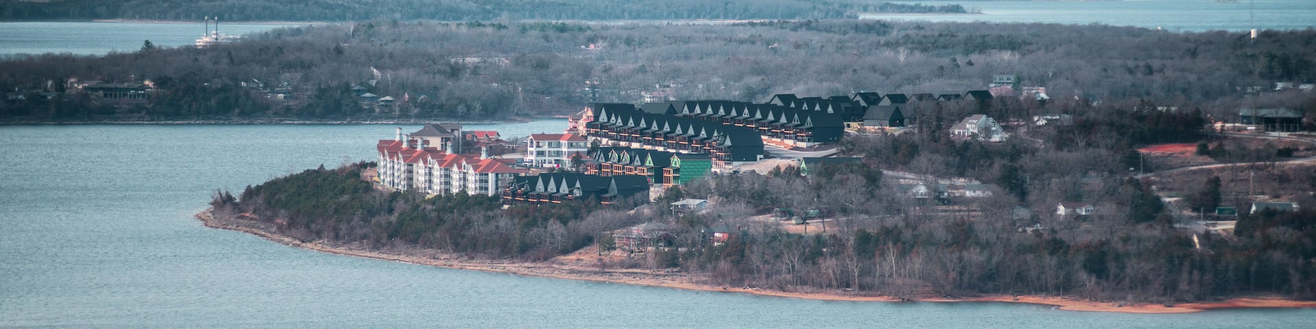 A lakeside resort with multiple buildings, a dock, and a forested shoreline.