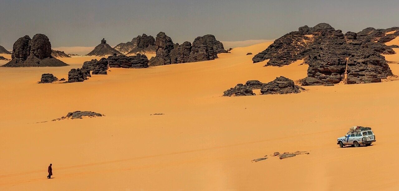 Paisatge desertic amb dunes de sorra i formacions rocoses.