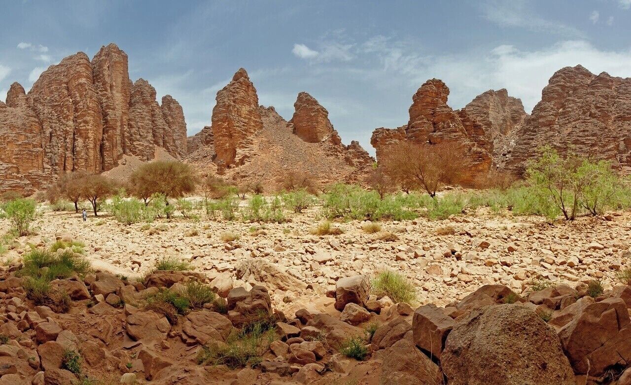 A rocky desert landscape with prominent sandstone formations and sparse vegetation.