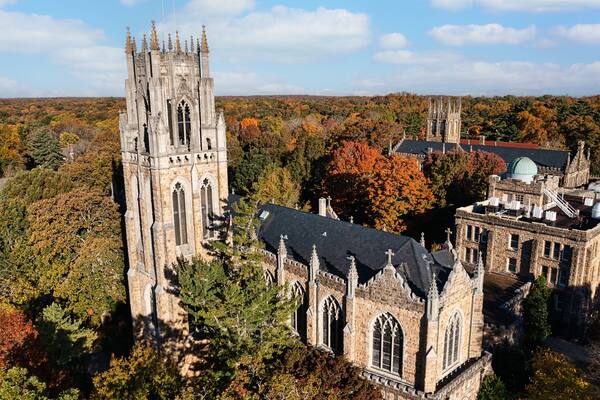 A historic church with a tall tower and a smaller building with a green dome, surrounded by autumn foliage.