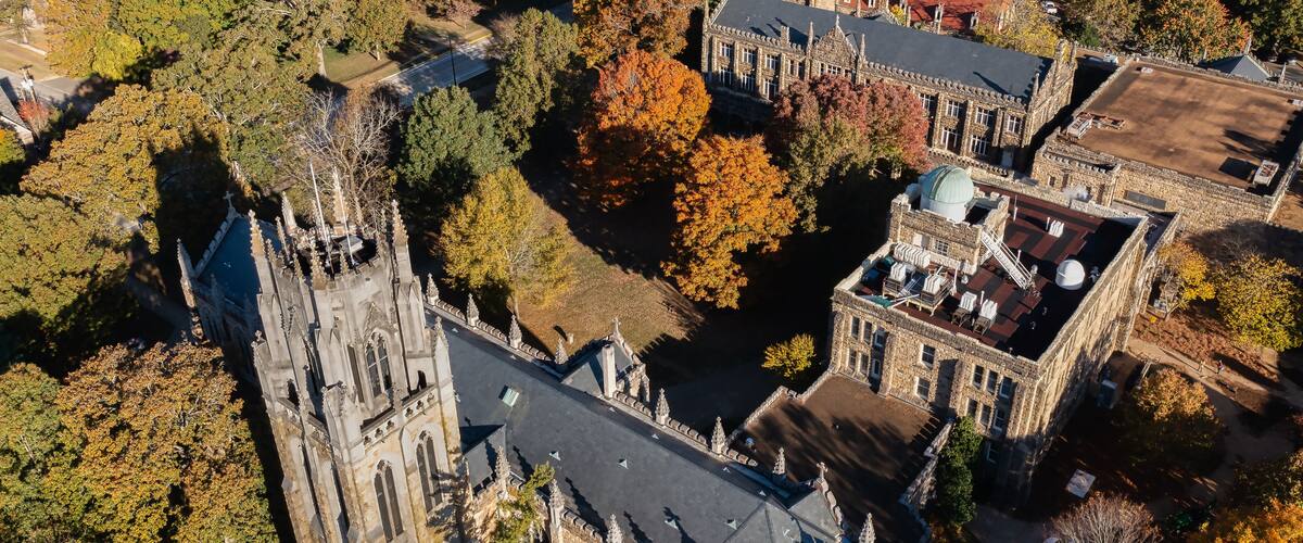 An aerial view of a historic building complex surrounded by autumn foliage.