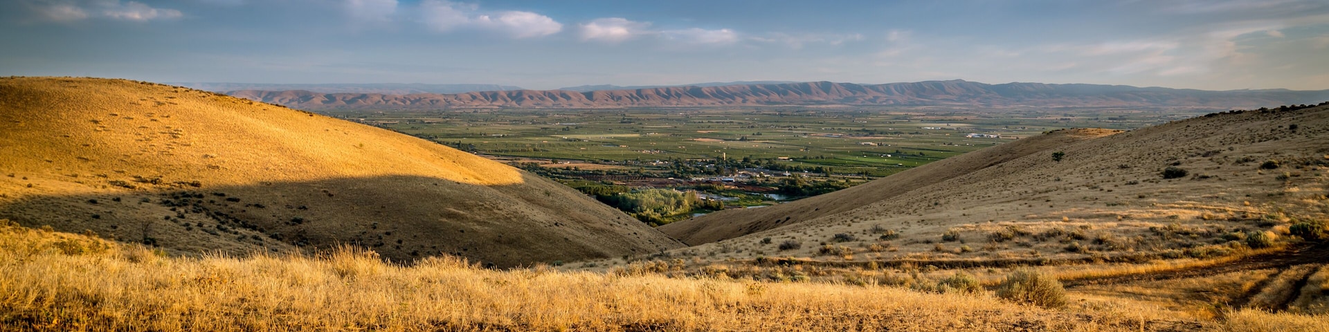 A valley with rolling hills and a distant town.