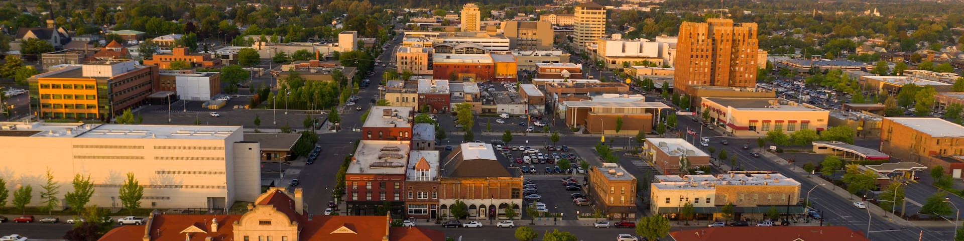 A cityscape with a prominent train station, a large building with a red roof, and a mountainous backdrop.