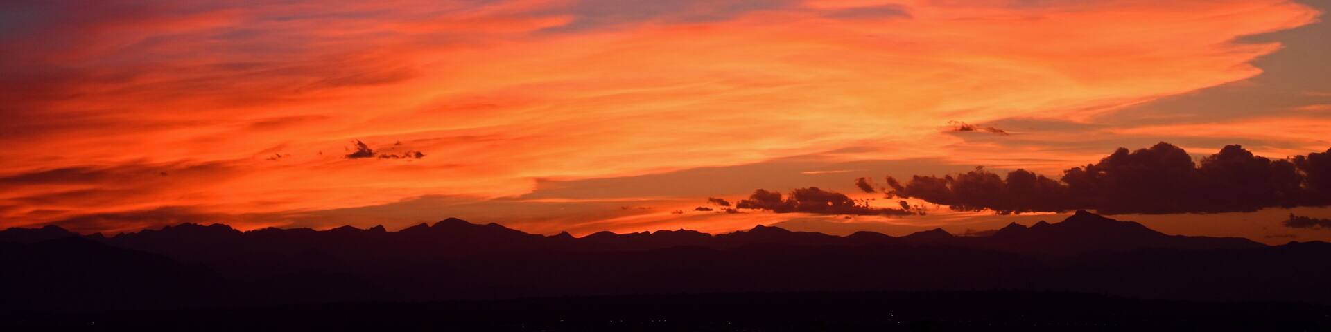A sunset over a mountain range with vibrant orange and red clouds.