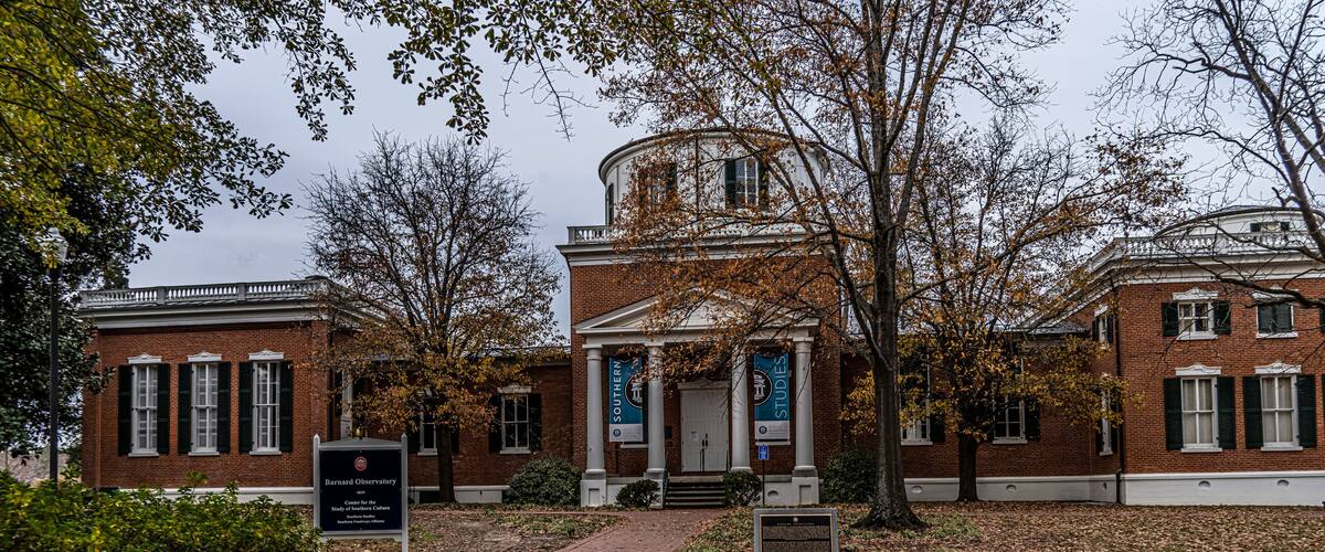 A historic building with a central dome, surrounded by trees and a brick facade.