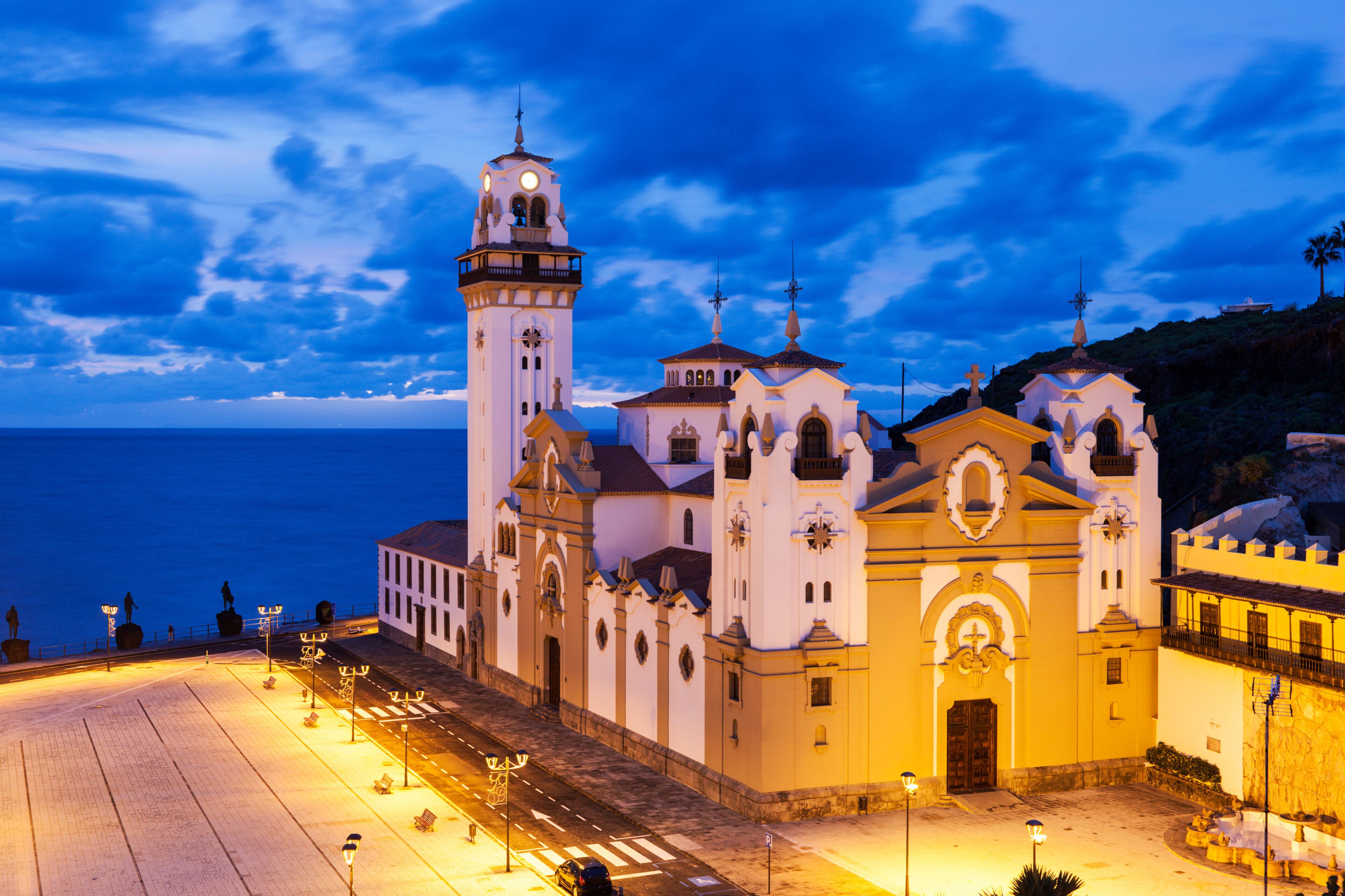A coastal church complex with a prominent bell tower and multiple smaller chapels, set against a twilight sky.